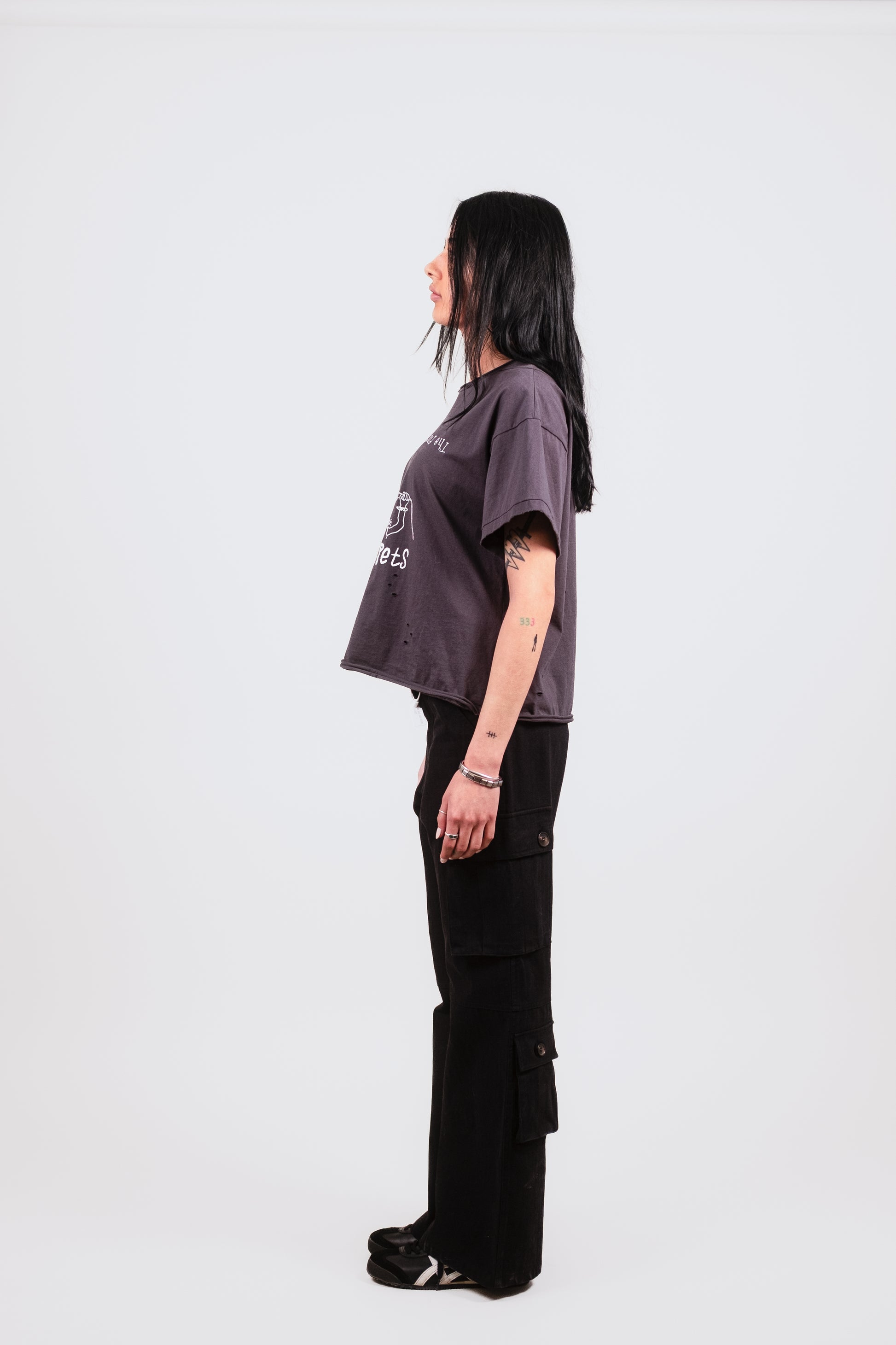 Profile of female model in Puppets Punk Tee — cropped luxury t-shirt with raw edges and bold white punk illustration, styled for elevated streetwear.