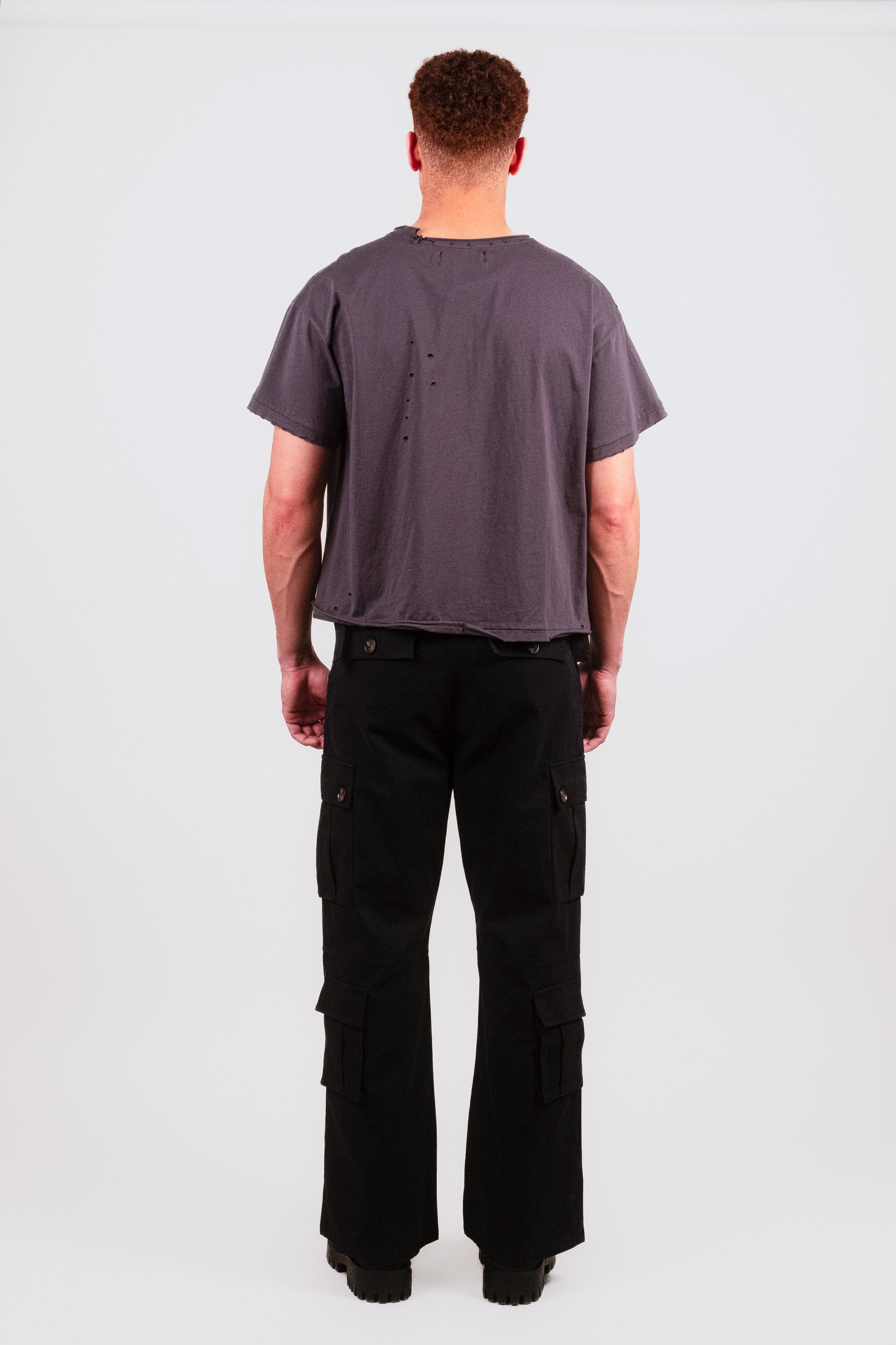 Back of male model in black cropped Puppets Punk Tee — showing clean minimal back panel with heavy garment processing and luxe vintage fade.