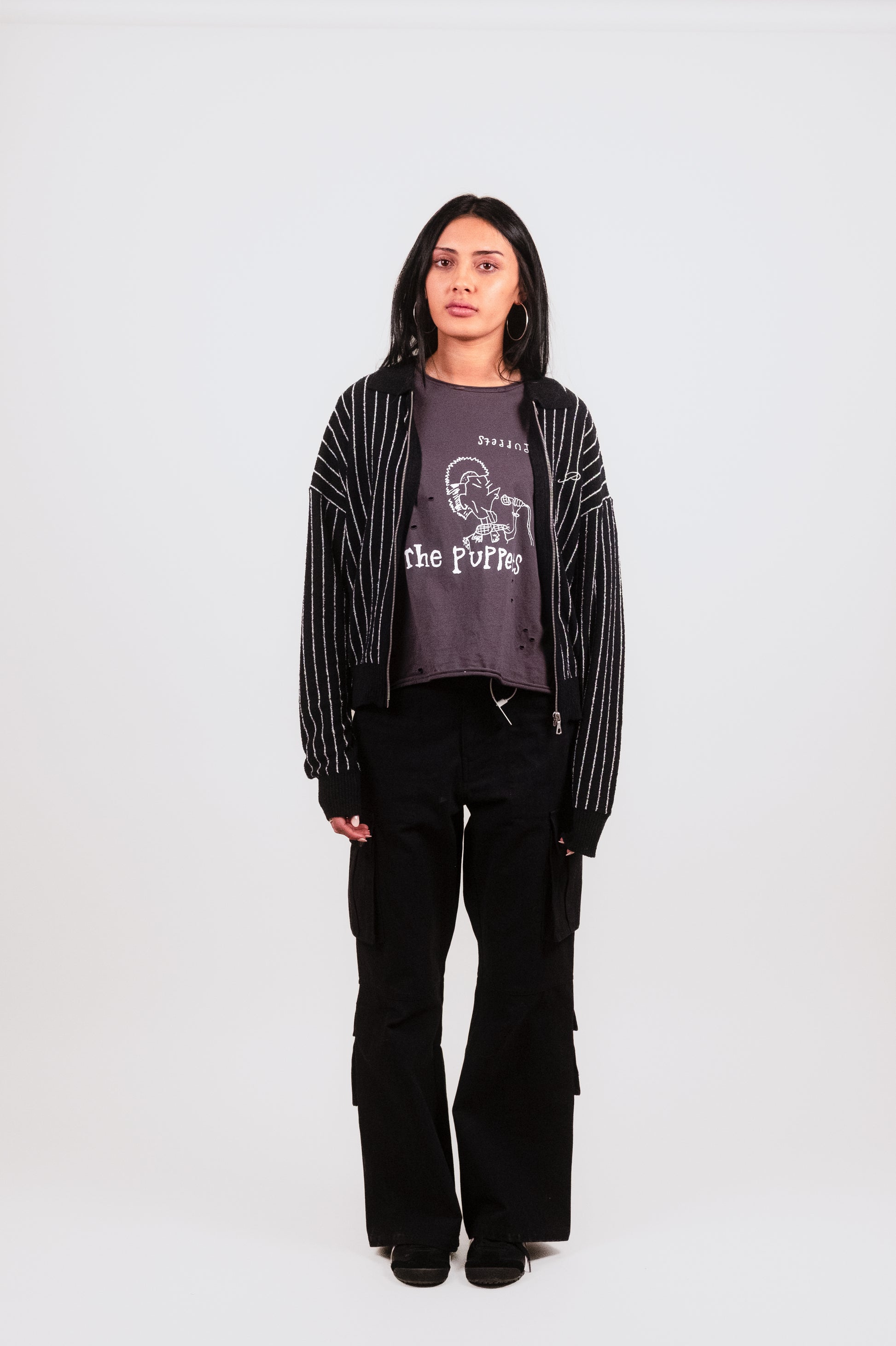 Anisa wears the black Posh Full Zip front-facing, emphasizing the tailored collar, bold white embroidery, and delicate boucle knit for a high-end streetwear layering piece.