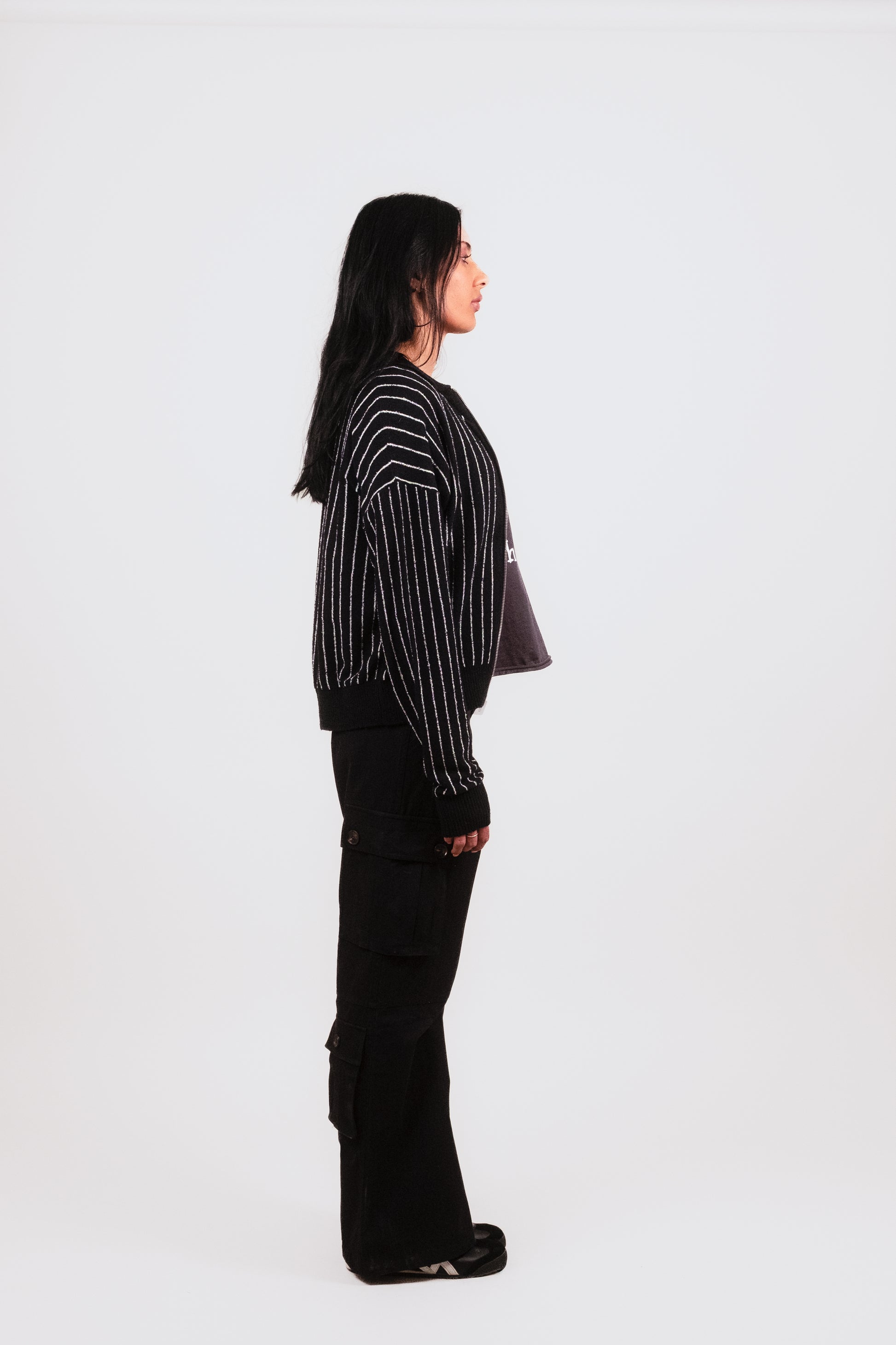 Alternate profile of Anisa in the black Posh Full Zip, capturing the signature embroidery, fine knit texture, and tailored menswear-inspired silhouette.