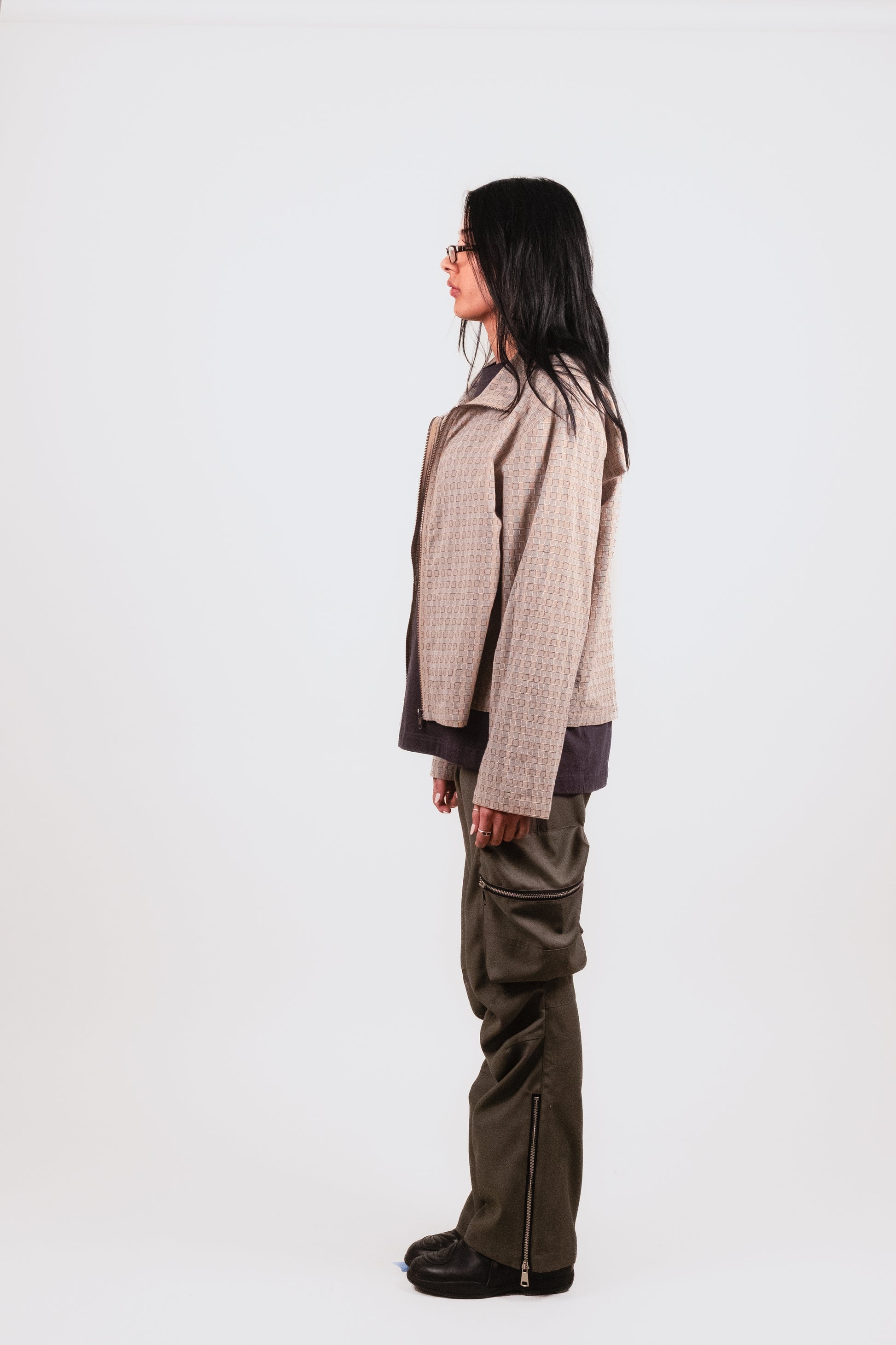 Female model profile in Technicalist Cargo — directional designer cargo trousers with sculptural articulation and subtle sheen - and Smart Zip — modern streetwear -meets-tailoring piece with architectural shape and clean detailing
