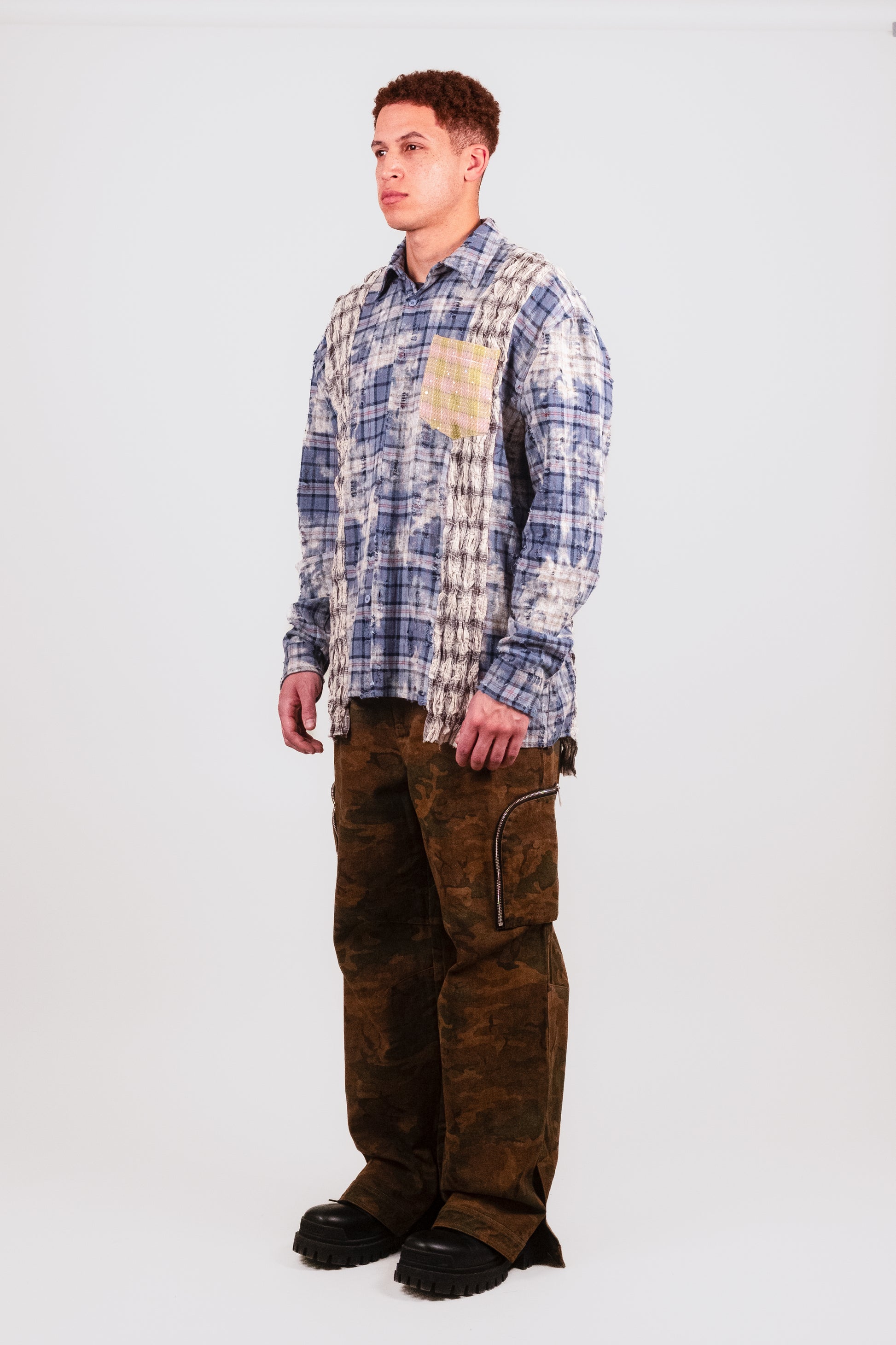 Angled view of male model in Fever Dream Flannel — streetwear flannel shirt with mixed fabric paneling, crystal-embellished pocket, and oversized, relaxed luxury fit.