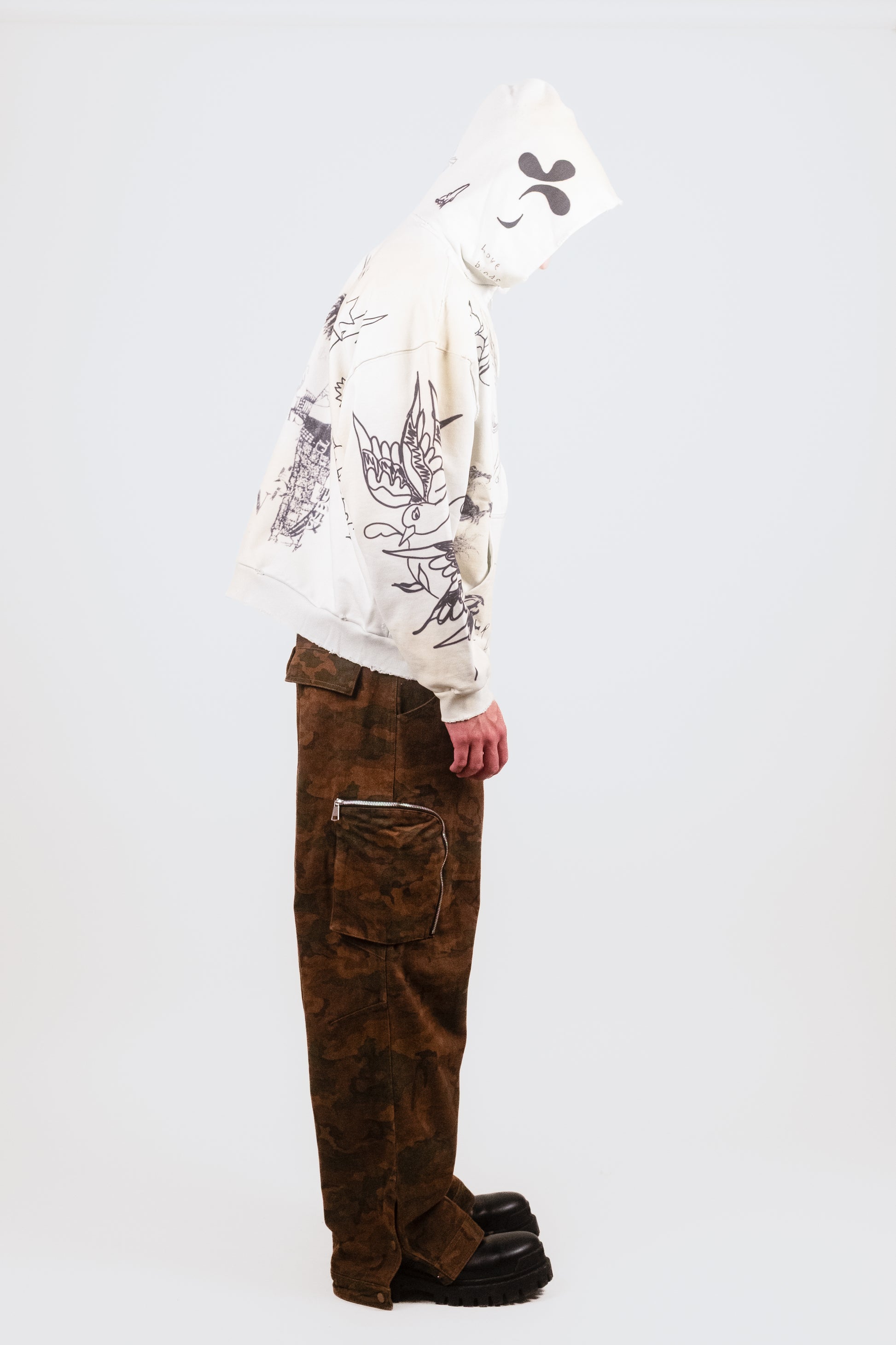 Alternate profile shot of Nate in the Second Skin Hoodie in Dove — emphasizing sleeve detailing, raw structure, and clean print application in a high-end streetwear context.
