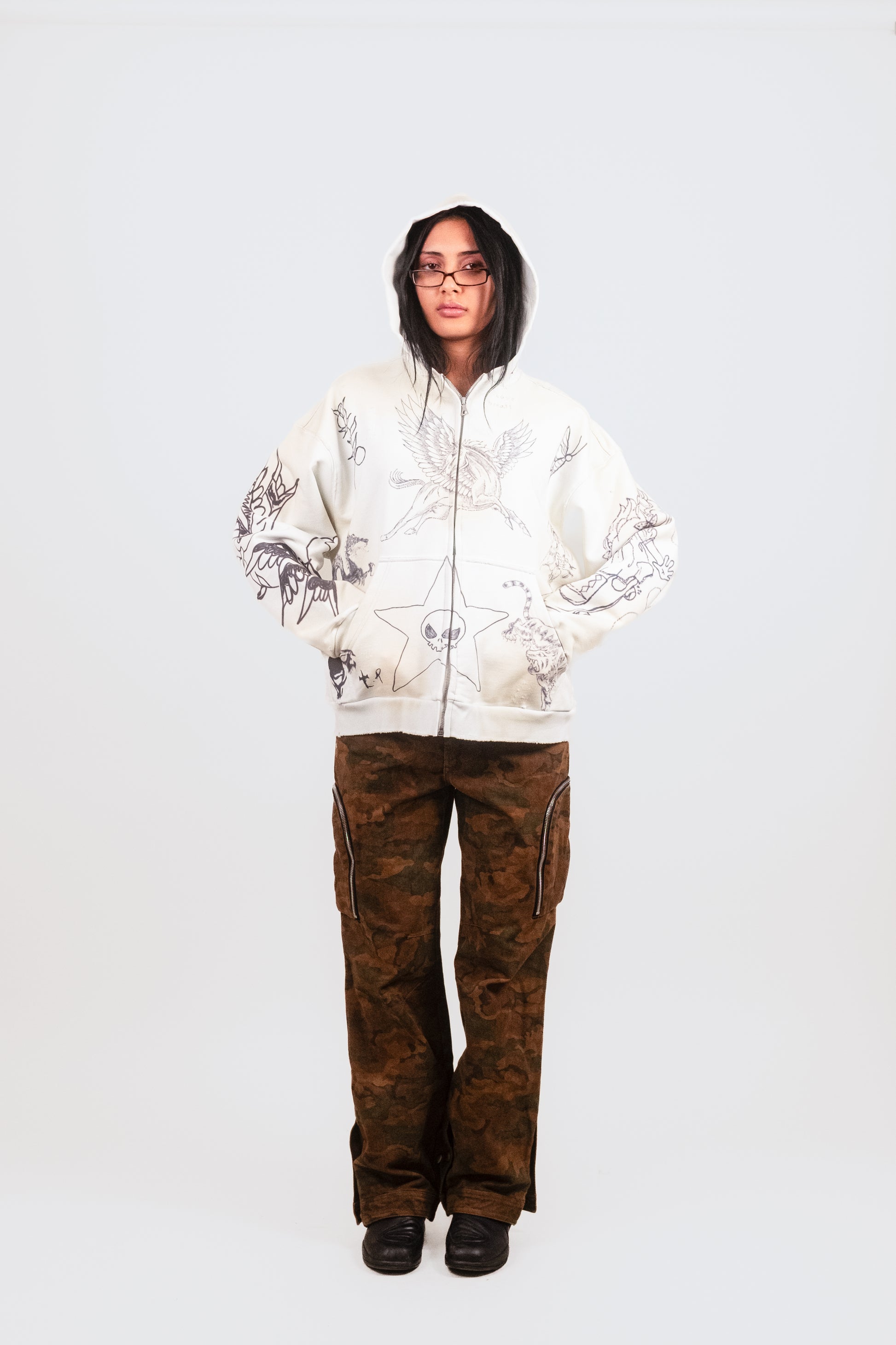 Anisa wears the Second Skin Hoodie in Dove in a front-facing pose, highlighting its crisp white hue with subtle blue undertones, original artwork, and contemporary streetwear fit.