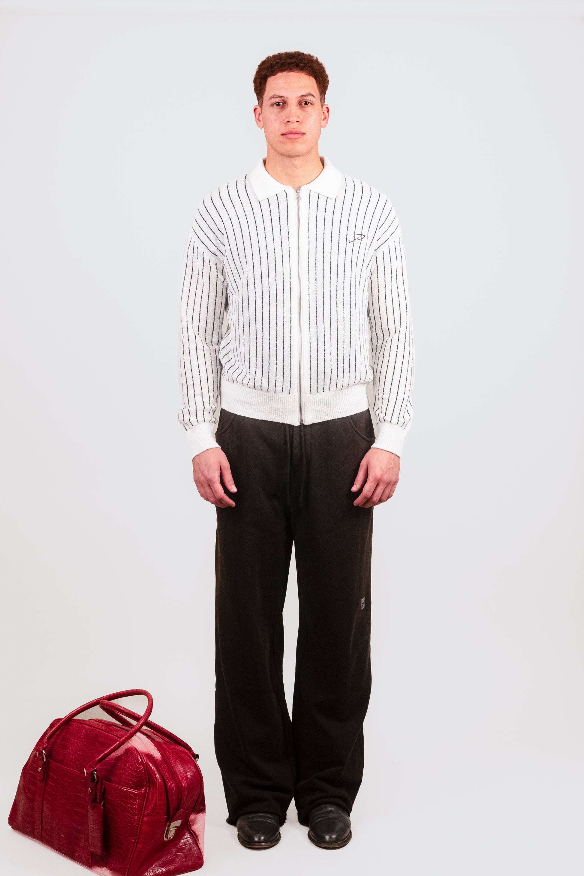 Nate models the Posh Full Zip in China White, highlighting the slim fit, delicate pinstripe pattern, and textured knit fabric as a refined streetwear layering piece.