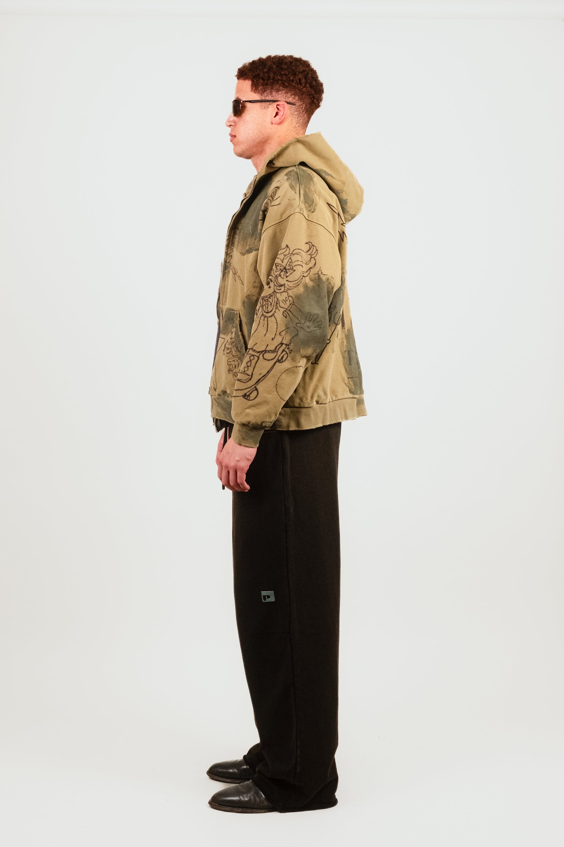 Nate’s profile shot in the Second Skin Hoodie in Grunge highlights the unique allover illustration treatment, cropped proportions, and luxury hand-finishing details in this elevated zip-up hoodie.