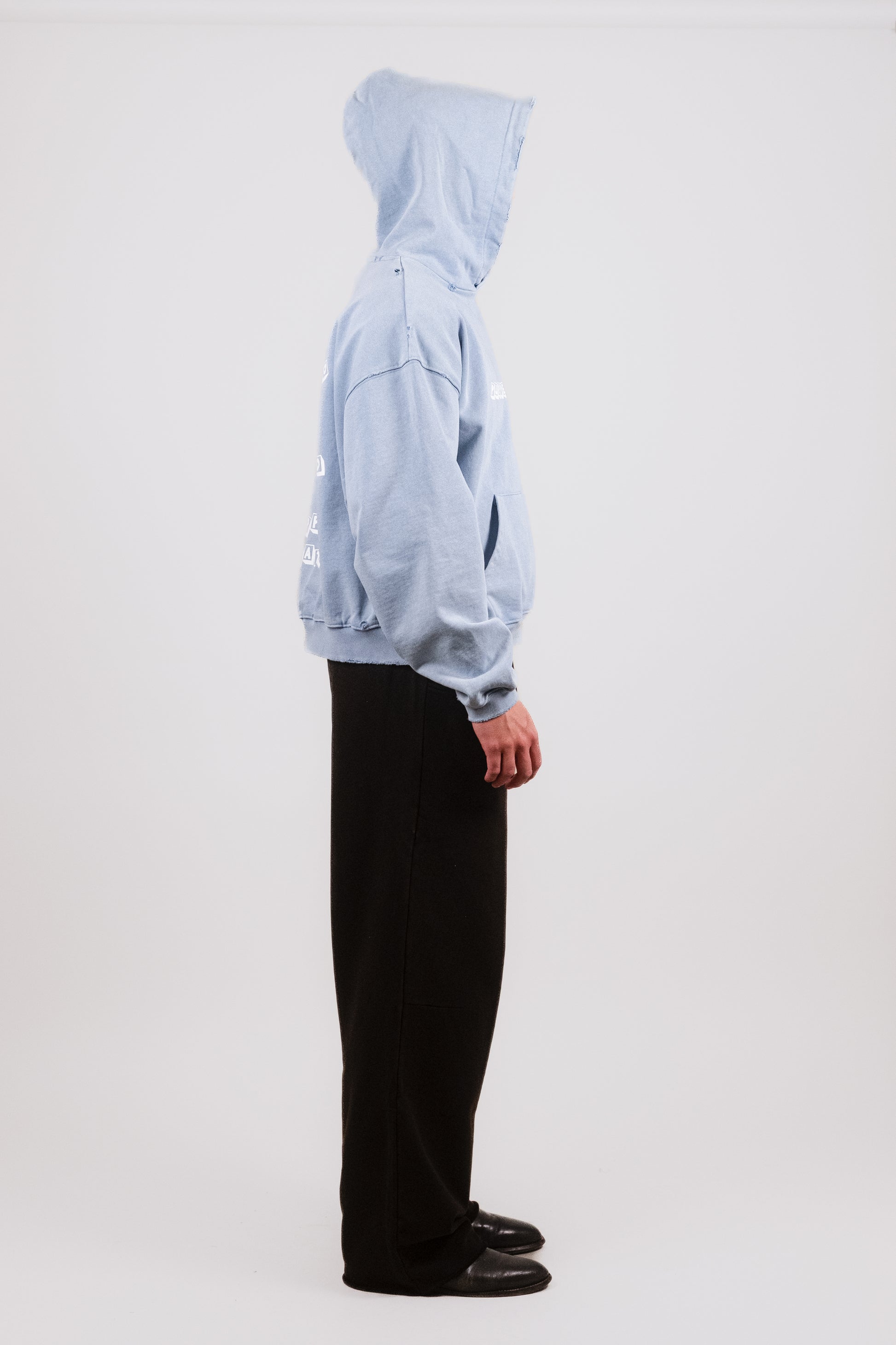 Alternate profile of Nate wearing the faded baby blue Reminiscence Block Logo Hoodie — luxury French terry streetwear piece featuring tonal fading, sleeve distressing, and minimal-yet-bold storytelling through archival graphic design.